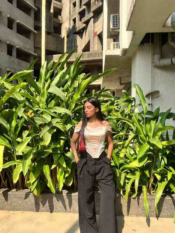 woman wearing a golden corset top and black flared trousers